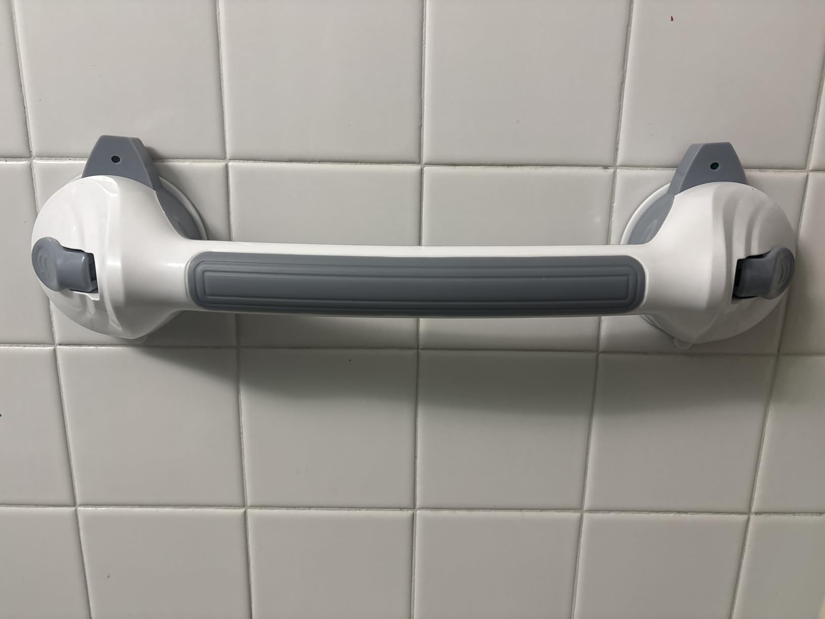 Grab bar mounted to white tile